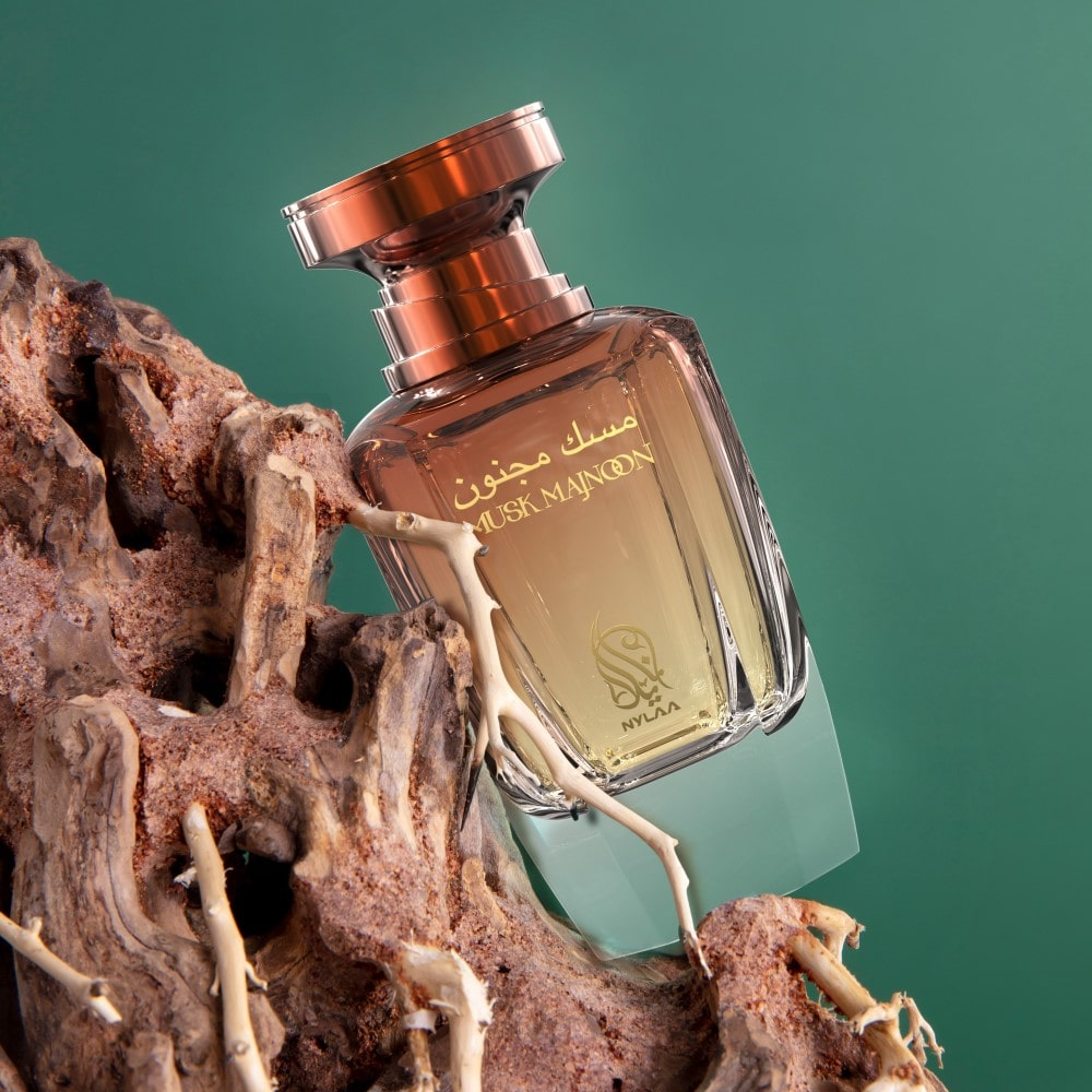 A brown & white perfume bottle with box from Nylaa by Savia Exclusive across a tree branch