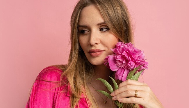 A girl holding pink flowers with a pink background