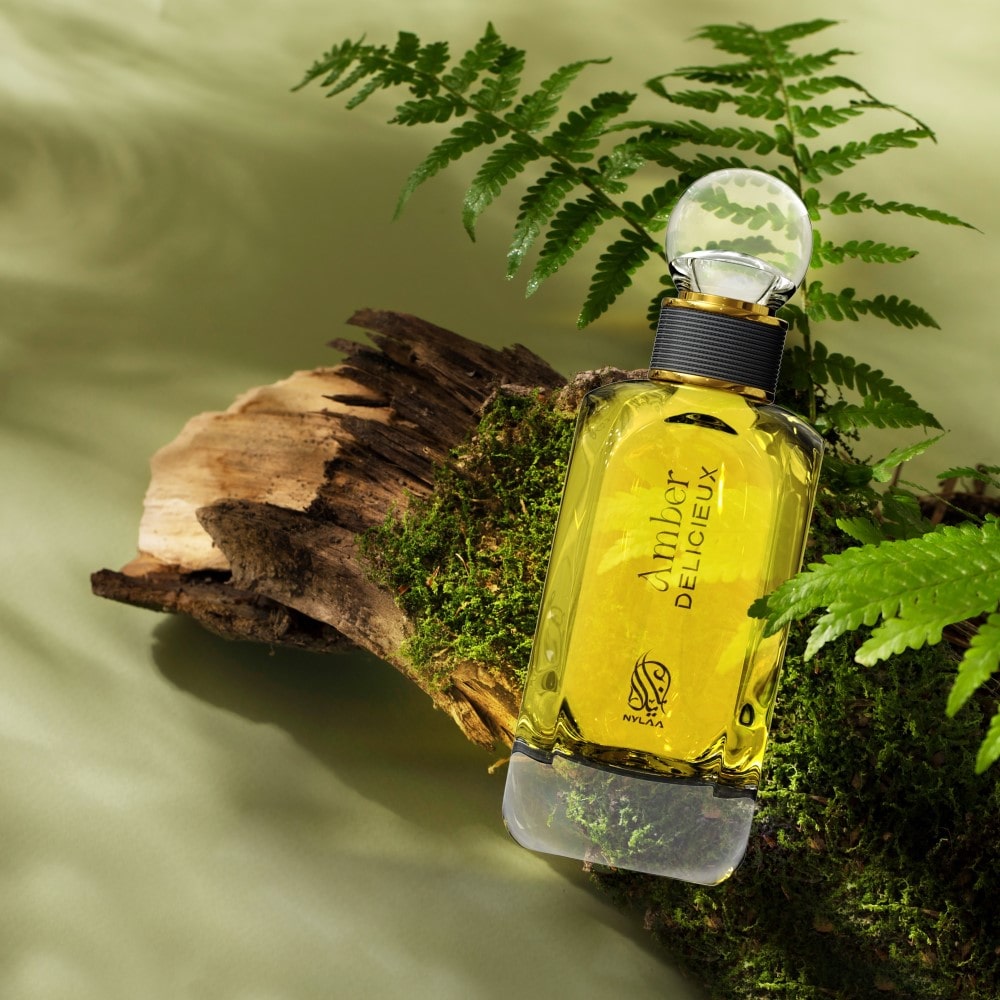 A light yellow perfume bottle by Savia Exclusive with a crystal cap on a brown oak branch with leaves