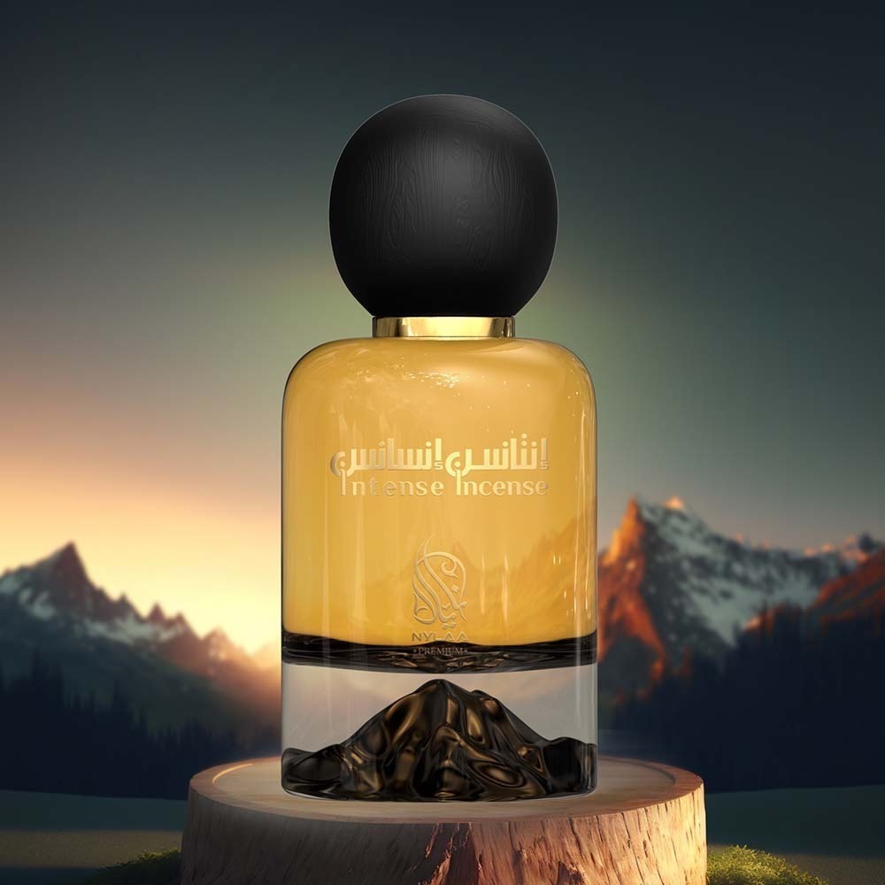 A golden perfume bottle with a black round cap from Nylaa by Savia Exclusive with mountains in the background