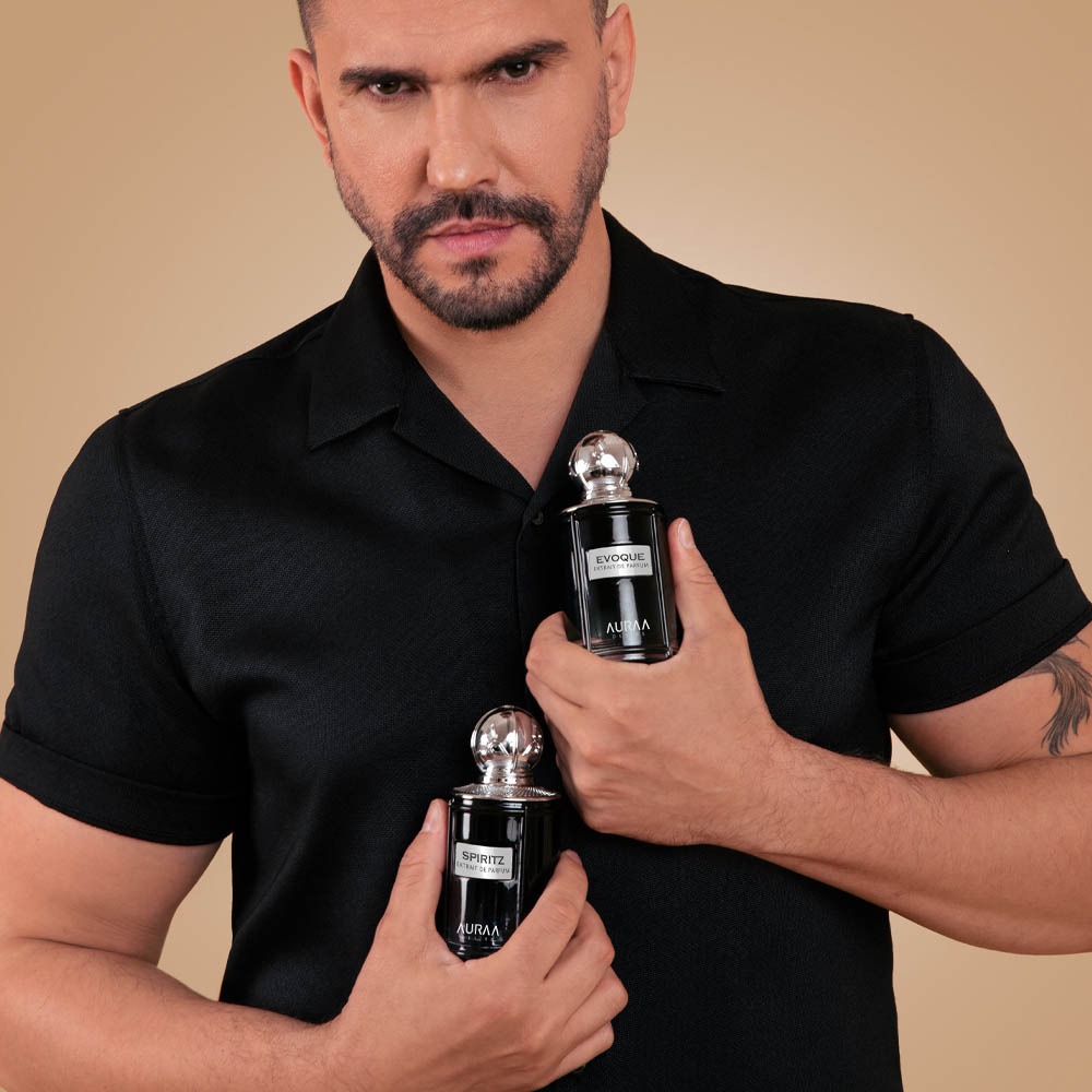 A man wearing a black t-shirt holding 2 luxury perfume bottles by Savia Exclusive